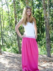 Adorable long haired teen chick taking off clothes in the shade of the trees near the sea.